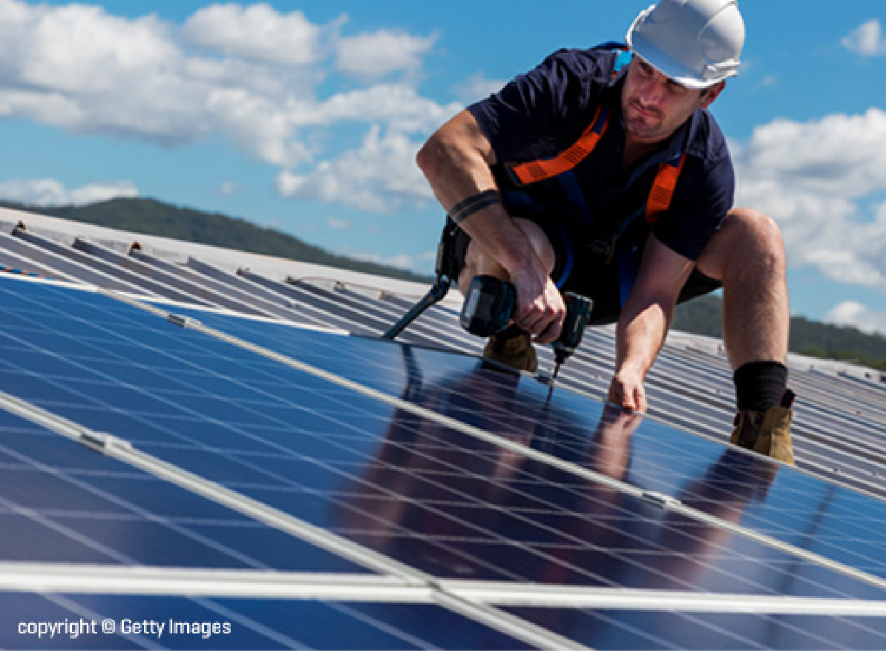 Man staat op het dak bij zonnepanelen